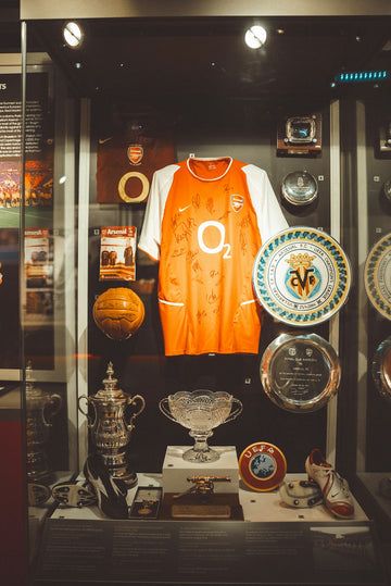 Arsenal football memorabilia displayed in a glass case.