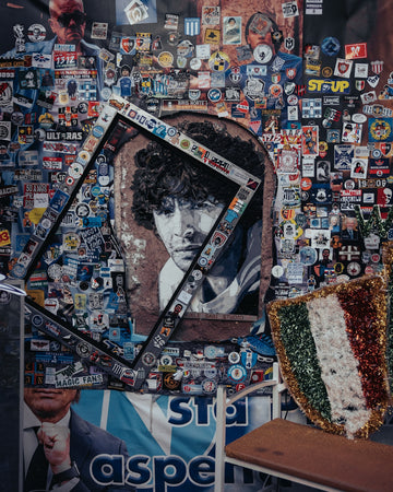 Wall covered in stickers with a framed portrait.