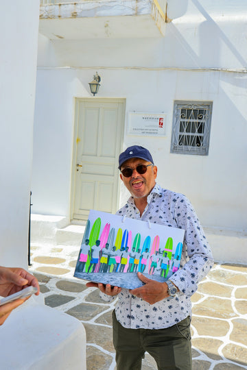 Man holding a gift bag with surfboards and people.