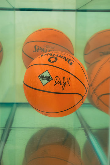 Several orange basketballs displayed in a shelf.