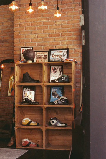 Wooden crate shelves displaying shoes against a brick wall.