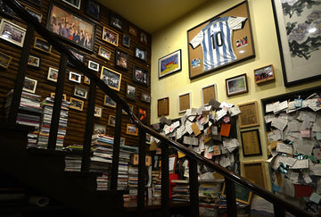 Staircase in room with walls full of framed memorabilia.