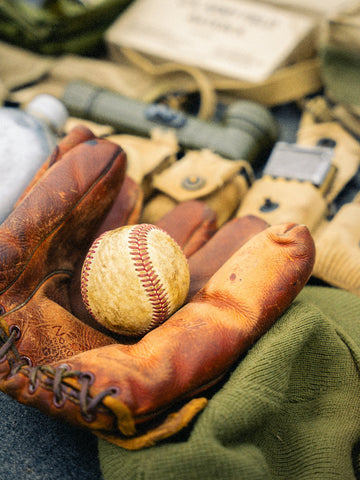 A vintage baseball and glove with military equipment.