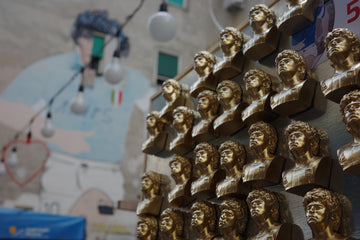 Golden busts arranged on a wall with a blurred mural.